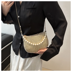 Detail of gold rhinestone mesh bag featuring large pearl handle and metal chain strap