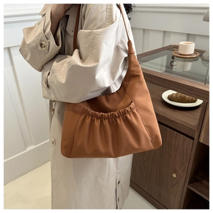 Détail du sac fourre-tout plissé caramel avec texture lisse porté avec un trench