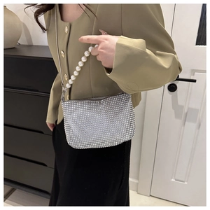 Close-up of sparkling silver rhinestone handbag with elegant pearl handle and metal chain