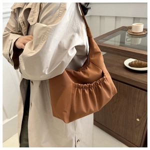 Sac bandoulière marron en nylon plissé présenté dans une scène de vie intérieure chaleureuse