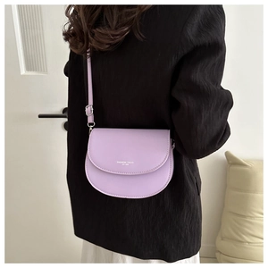 Détail du sac selle violet lavande avec inscription argentée tendance et texture cuir mat