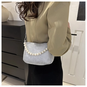 Close-up of silver rhinestone shoulder bag with pearl strap and metal chain details