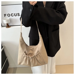 Détail d'un sac hobo en nylon beige avec poche plissée sur un mannequin minimaliste