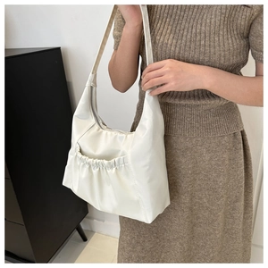 Détail du sac bandoulière hobo crème avec une poche avant décorative à plis souples