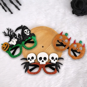 Three assorted Halloween party glasses featuring pumpkin and skeleton designs on a wood tray