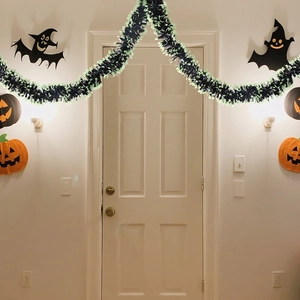 Black and green Halloween garland with bat and pumpkin wall stickers on a white door