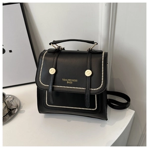 Detail of black faux leather backpack with gold buckles and beaded piping finish