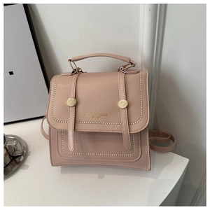 Close-up of pink leather travel backpack featuring golden buckles and stitched straps