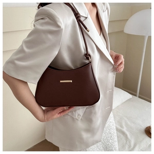 Detail view of a vintage dark brown leather underarm bag styled with a beige suit