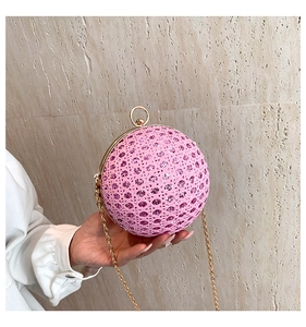 Detailed close-up of pink glitter sphere clutch with gold handle and chain strap