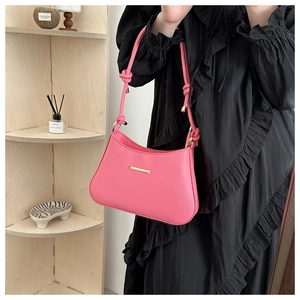 Detailed view of pink leather underarm bag with knot strap and gold metal hardware