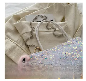 Gros plan d'un sac à main pailleté iridescent avec chaîne et breloque peluche rose