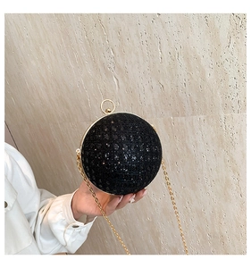 Detail of black spherical evening clutch bag with sequins and golden chain strap