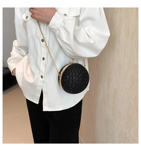Detail of a sparkling black spherical evening bag with rhinestones and gold chain