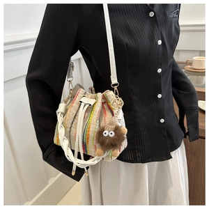 Detail of colorful striped woven bucket bag with white leather straps and plush charm