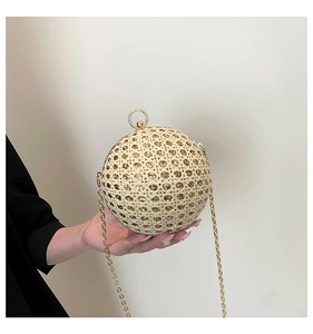 Detail of spherical evening bag with beige woven texture, gold sequins, and ring handle