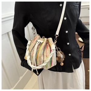 Detailed close-up of colorful striped knit bucket bag with a cute brown bear charm
