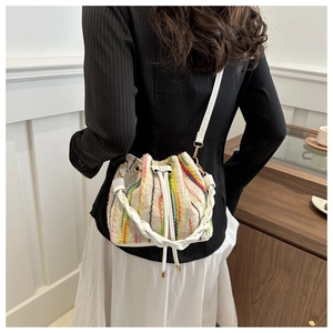 Detail of cream bucket bag with colorful striped embroidery and woven handle