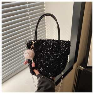 Détail d'un sac seau noir à paillettes avec chaîne argentée et breloque en peluche rose