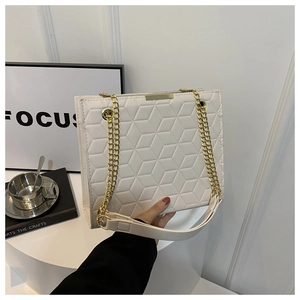Detail of white 3D geometric embossed texture and gold chain on the crossbody bag