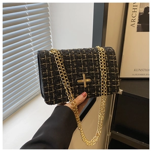 Detailed close-up of retro black tweed fabric texture and gold metal turn-lock on crossbody bag