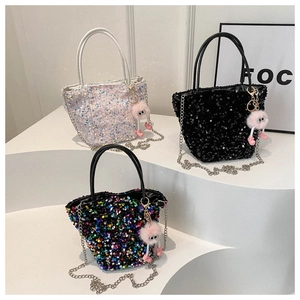 Détail de sacs à paillettes avec poignées brillantes, chaînes en métal et breloque rose