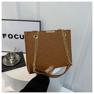 Detail of brown embossed leather handbag with gold chain strap and square texture