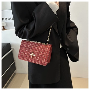 Close-up of a red tweed chain bag with gold hardware worn by a model in a black suit