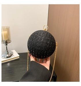 Close-up of black sphere clutch bag with glittering sequins and gold chain strap