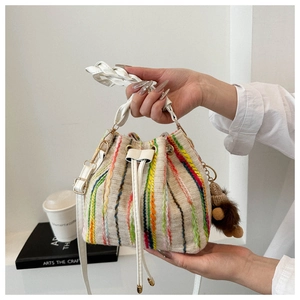 Detail of knitted rainbow drawstring bucket bag with plush bear charm and handle