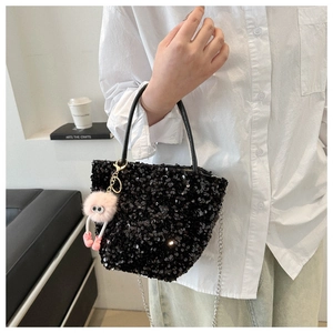 Gros plan du sac à main à paillettes noires avec chaîne et charm peluche rose
