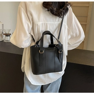 Détail d'un grand sac cabas noir avec garnitures dorées et bandoulière réglable