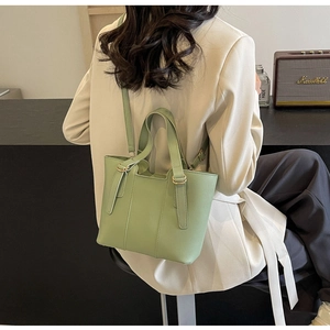 Détail du sac cabas vert clair avec texture litchi et bandoulière sur un mannequin