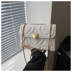 Detail of white leather heart quilted bag with gold heart-shaped lock and chain strap