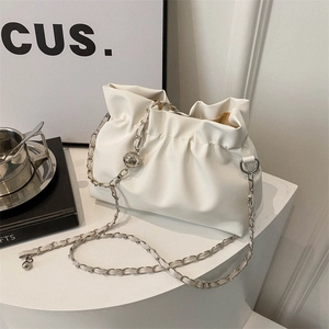 Sac seau blanc élégant avec chaîne argentée présenté sur un support d'exposition épuré