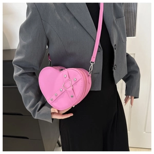 Détail du sac à bandoulière rose en forme de cœur avec rivets argentés et anneau en métal