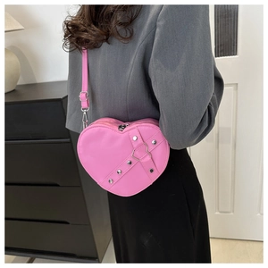 Détail du sac cœur rose avec des rivets métalliques et un design de sangles croisées