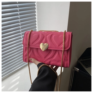 Close-up of bright pink bag featuring heart quilting and gold heart-shaped metal clasp