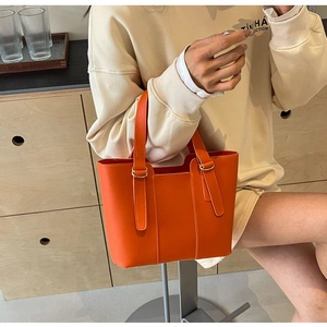 Détail d'un sac cabas en cuir PU orange avec des boucles en métal doré élégantes