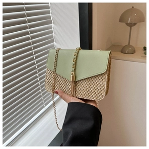 Detail of green leather flap and beige straw weave texture on chain shoulder bag