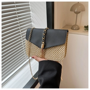 Detail of straw woven crossbody bag with black leather flap and gold tassel fringe