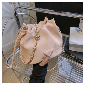 Detail of pink bucket bag featuring drawstring closure and golden chain strap
