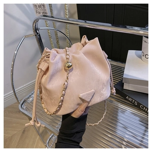 Detail of pink faux suede bucket bag with gold ball chain strap and drawstring closure