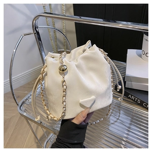 Detail of a white satin drawstring bucket bag with gold chain and metal emblem
