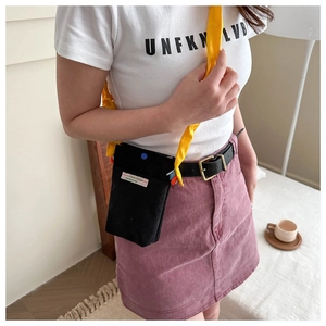 Detail of black corduroy mini crossbody bag with yellow strap and fashion patch
