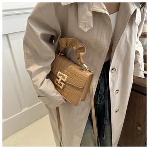 Detail of khaki croc-embossed square handbag featuring decorative ruffle handle and gold hardware
