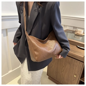 Detail of a brown PU leather hobo bag featuring natural lychee texture and crescent shape