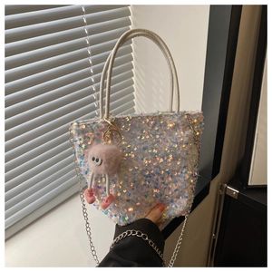 Détail du sac à main à paillettes avec breloque en peluche rose et chaîne argentée