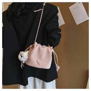 Pink suede bucket bag featuring drawstring closure, metal chain, and white bear charm detail