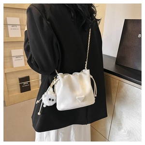 Detail of white leather drawstring bucket bag with gold chain strap and plush charm